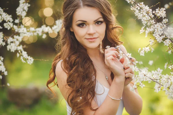 Retrato de la joven morena en el jardín floreciente de primavera — Foto de Stock