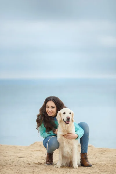 Porträtt av vacker ung kvinna leker med hunden vid havet — Stockfoto