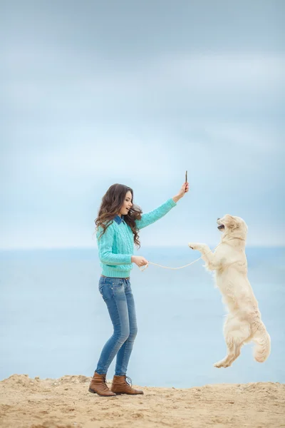 Retrato de bela jovem mulher brincando com o cão na costa do mar — Fotografia de Stock