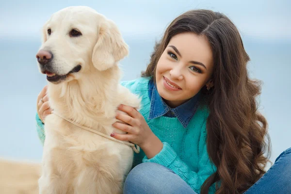 Porträtt av vacker ung kvinna leker med hunden vid havet — Stockfoto