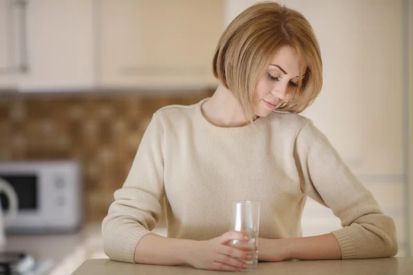 Bella donna in cucina con un bicchiere d'acqua — Foto Stock