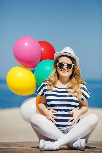 Mujer embarazada en gafas de sol y un sombrero blanco con globos —  Fotos de Stock