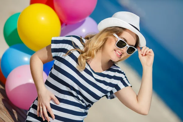 Gravid kvinna i solglasögon och en vit hatt med ballonger — Stockfoto