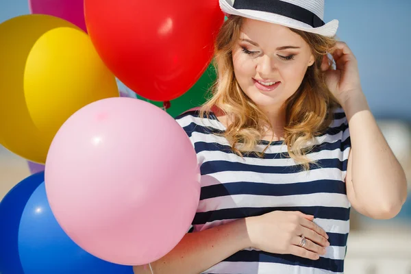 Hamile kadın güneş gözlüğü ve balonlar ile beyaz bir şapka — Stok fotoğraf