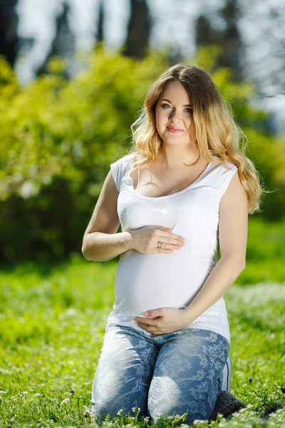 Stående frisk gravid kvinna sitter på grönt gräs — Stockfoto