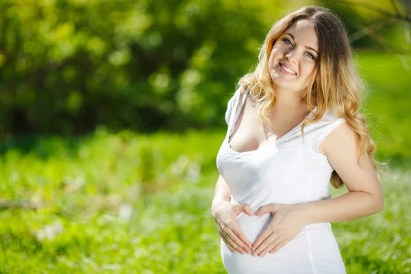 Stående frisk gravid kvinna sitter på grönt gräs — Stockfoto