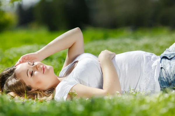 Portrait of a pregnant woman lying on green grass in the park — Stock Photo, Image