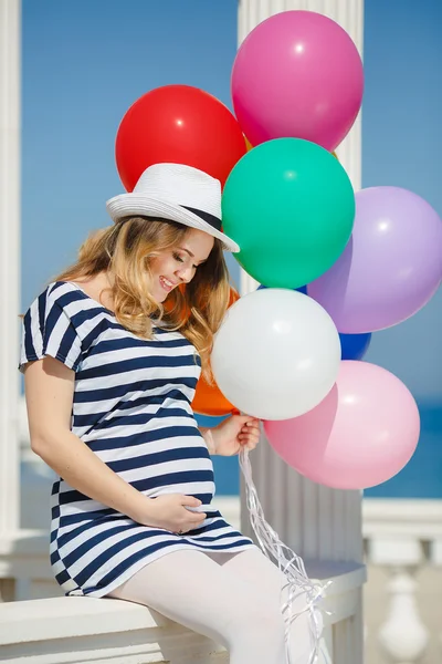Pregnant woman in sunglasses and a white hat with balloons Stock Image