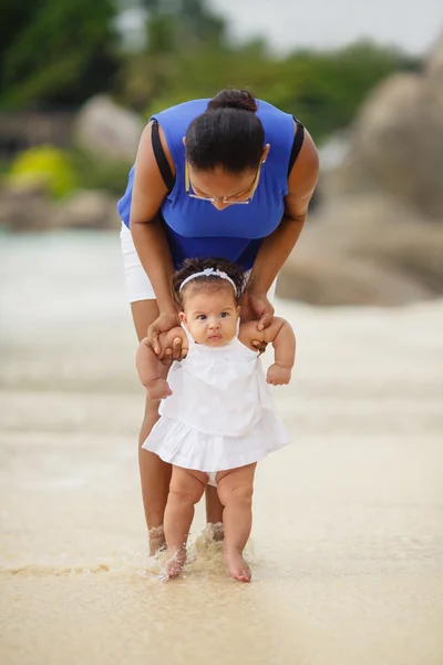 Ung glad mamma med ett barn på stranden — Stockfoto