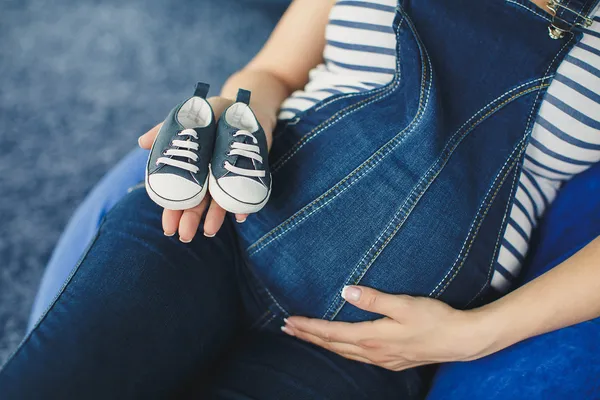 Imagem recortada de uma mulher grávida pequenos sapatos — Fotografia de Stock