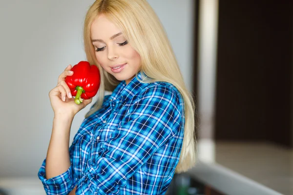 Woman in the kitchen with red pepper in hand — Stock Photo, Image