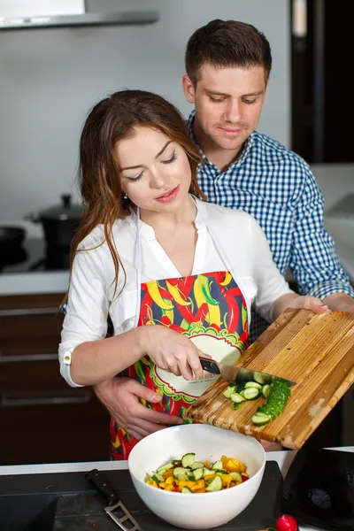 Ungt par att göra en sallad tillsammans i köket — Stockfoto