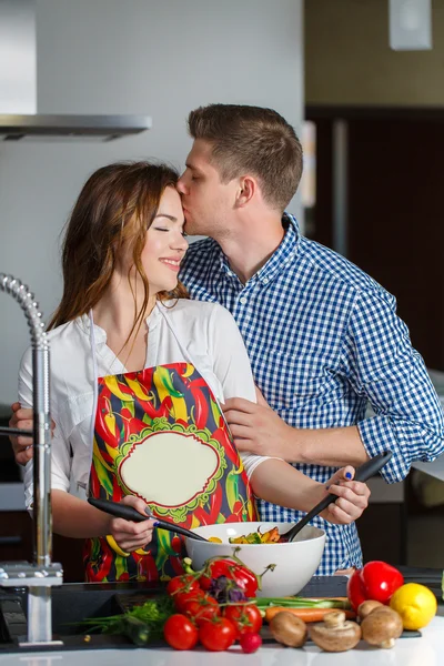 Pareja joven haciendo una ensalada juntos en la cocina —  Fotos de Stock