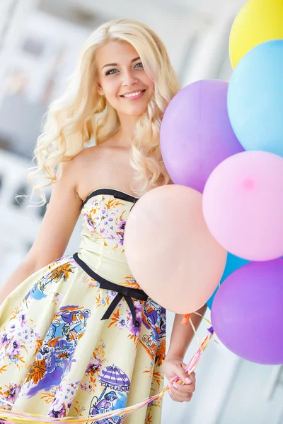 Красивая улыбающаяся блондинка с цветными воздушными шарами — стоковое фото
