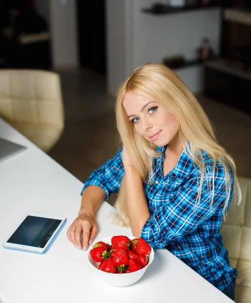 Glückliche junge Hausfrau mit Tablet-PC, die Früchte isst — Stockfoto