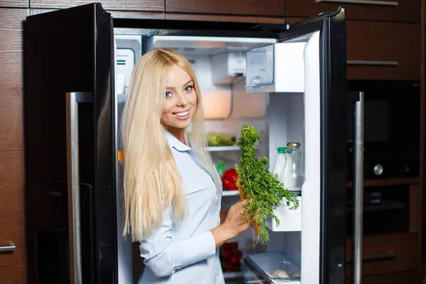 Hermosa joven cerca de la nevera con comida saludable . — Foto de Stock