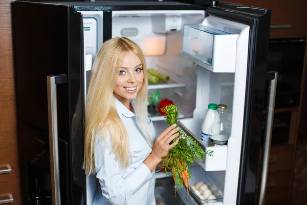 Hermosa joven cerca de la nevera con comida saludable . — Foto de Stock