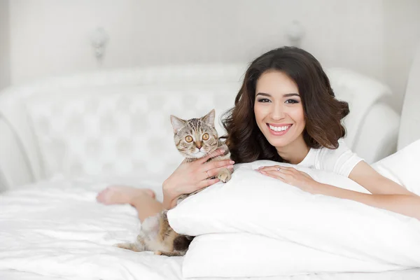 Ung kvinna spelar på sängen med katten — Stockfoto