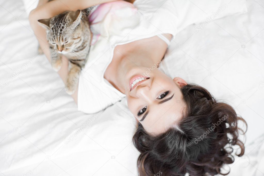 Young woman playing on the bed with the cat