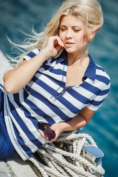 Adorable mujer rubia con pantalones cortos de mar y sexy marinero camiseta sentado en el fondo de yates y el mar —  Fotos de Stock