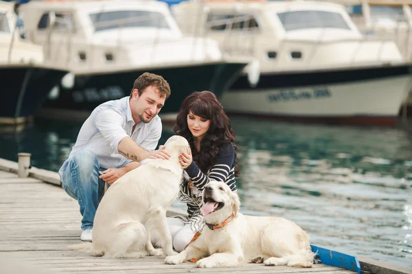 Young couple playing with a dog in the harbor — Stock Photo, Image