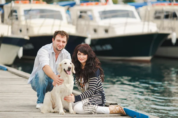 Young couple playing with a dog in the harbor — Stock Photo, Image