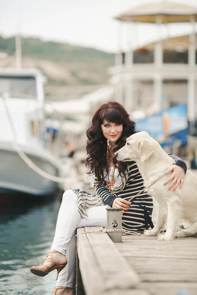 Mooi meisje met een hond aan de promenade in de buurt van de zee. — Stockfoto