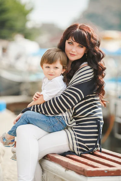 Happy mother and son sitting on the quay. — Stock Photo, Image