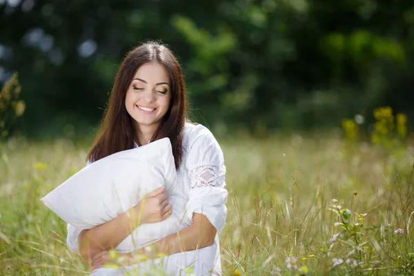 A menina com um travesseiro na grama fresca da primavera . — Fotografia de Stock