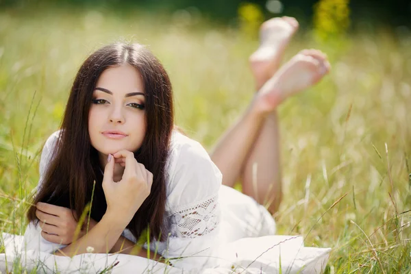 Девушка с подушкой на свежей весенней траве . — стоковое фото
