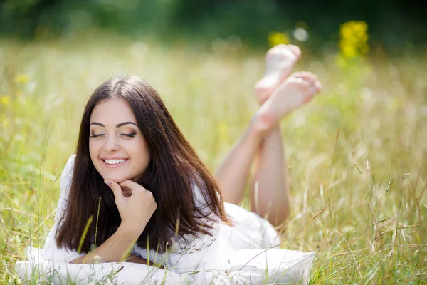 Das Mädchen mit dem Kopfkissen auf dem frischen Frühlingsgras. — Stockfoto