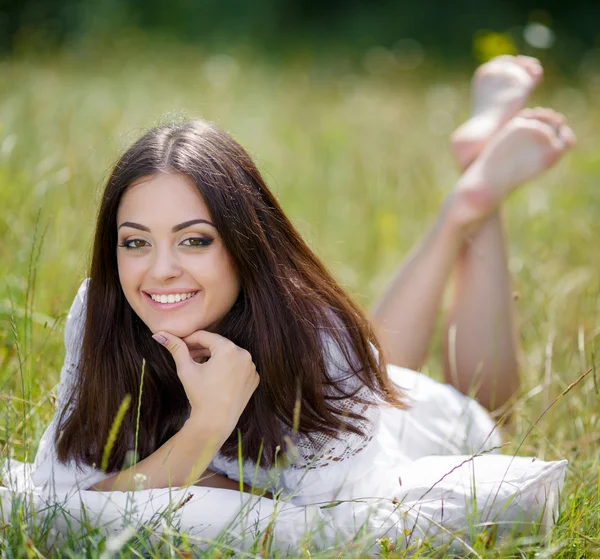 Dívka s polštářem na čerstvá jarní tráva. — Stock fotografie