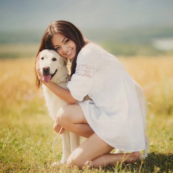 Hermosa mujer juega con el perro en el prado — Foto de Stock