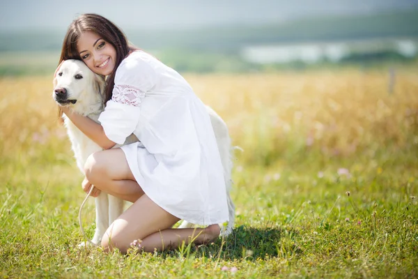 Hermosa mujer juega con el perro en el prado — Foto de Stock