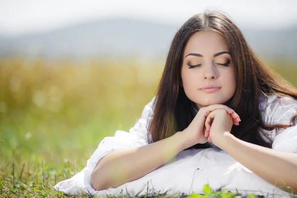 The girl with a pillow on the fresh spring grass. — Stock Photo, Image