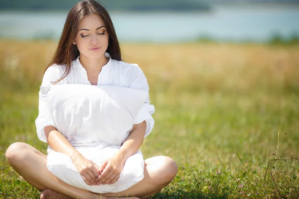 Fille appuyé sur un oreiller doux sur des herbes fraîches de printemps . — Photo