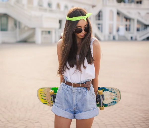 Beautiful and fashionable young woman posing with skateboard — Stock Photo, Image