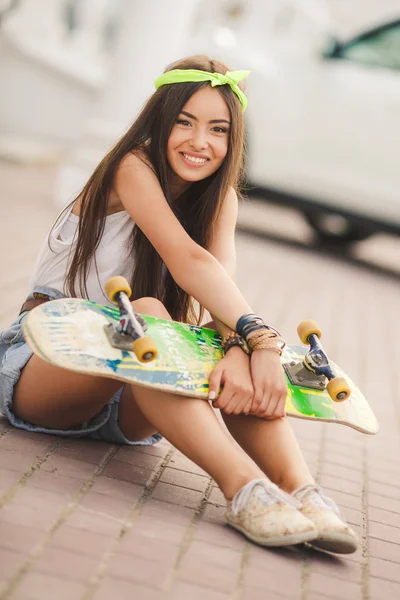 Beautiful and fashionable young woman posing with skateboard — Stock Photo, Image