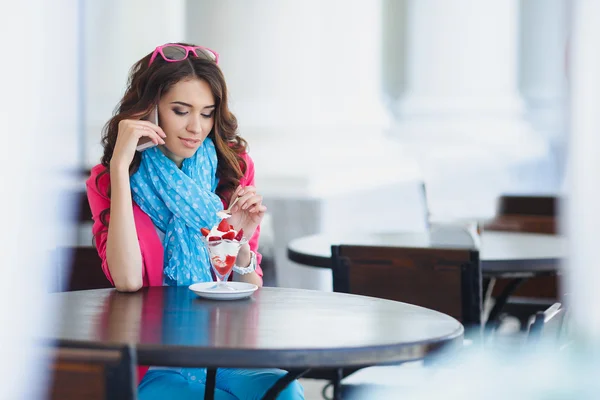 Young beautiful woman eating dessert and talking on the phone. — Stock Photo, Image
