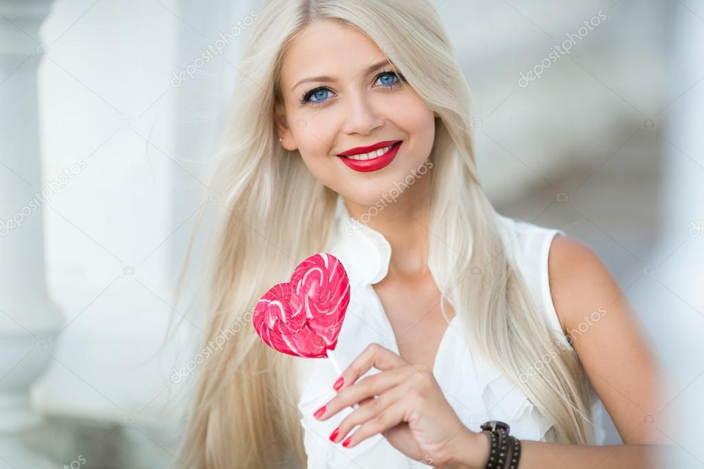 Elegant blonde with a lollipop in the shape of a heart