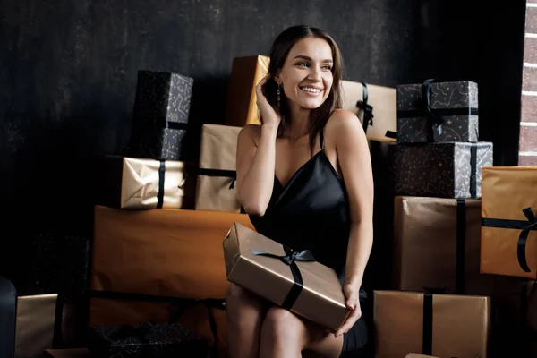 Young happy laughing woman in black dress with gifts — Stock Photo, Image