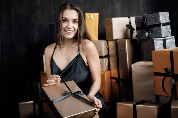 Fiatal boldog nevető nő fekete ruhában ajándékokkal — Stock Fotó