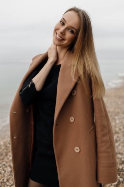 Paltolu ve gözlüklü genç bir kadının portresi. Sahilde sonbaharda.