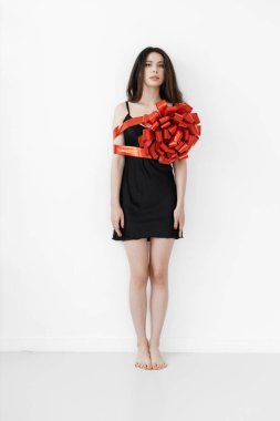 Kurdeleyle sarılmış genç, güzel bir kadın, kırmızı hediye kurdelesi.