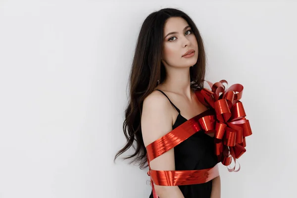 Junge hübsche Frau mit Schleife umwickelt, rotes Geschenkband — Stockfoto