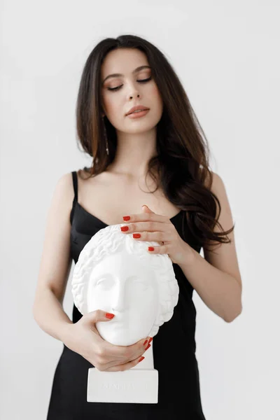 Young woman in black dress with statues head — Stock Photo, Image