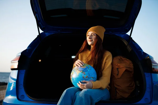 Cute casual woman ready for travel with globe in car — Stock Photo, Image