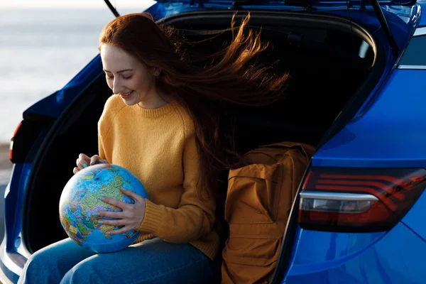 Cute casual woman ready for travel with globe in car — Stock Photo, Image