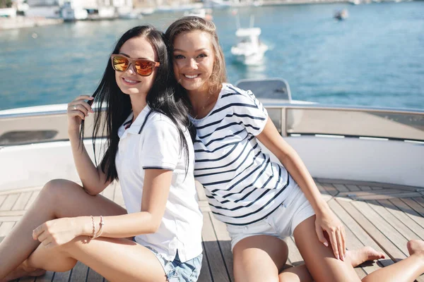 Cute young females on a luxury yacht near rocks in the sea — стоковое фото