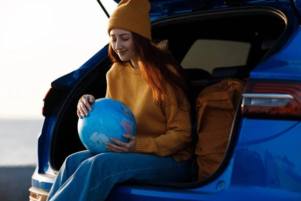 Cute casual woman ready for travel with globe in car — Stock Photo, Image